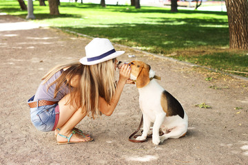  girl kissing her beagle dog in nature outdoors.