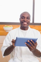 Happy man in bathrobe using tablet pc