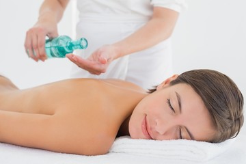Obraz na płótnie Canvas Attractive woman getting massage oil on her back