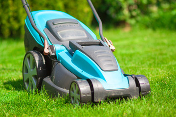 blue lawn mower on green grass. cut the grass