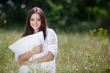 Girl leaning on a soft pillow on fresh spring herbs.