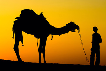 Silhouette man and camel at sunset in desert, Jaisalmer, India