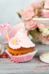 Tasty cup cake with cream on grey wooden table