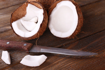 Broken coconut with knife on wooden background