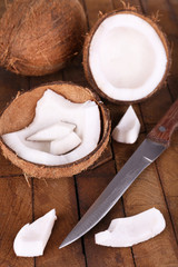 Broken coconut with knife on wooden background