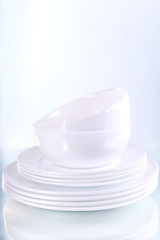 Set of white dishes on table on light background