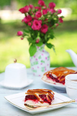 Coffee table with teacups and tasty pie in garden