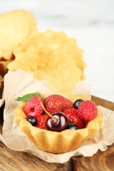 Tasty tartlets with berries on wooden table