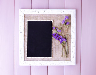Wooden frame with dried flowers and old blank photo