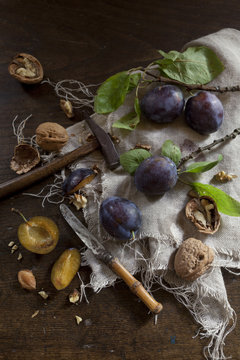 Prunes with leafs and walnuts on rustic background