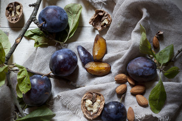 Prunes with leafs, walnuts, almonds on rustic background