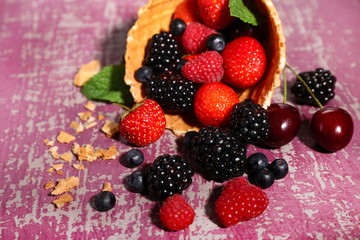 Fototapeta na wymiar Different ripe berries in sugar cone, on purple background