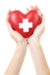 Red heart with cross sign in female hand, close-up, isolated