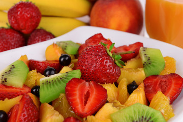Fresh fruits salad on plate with berries and juice close up