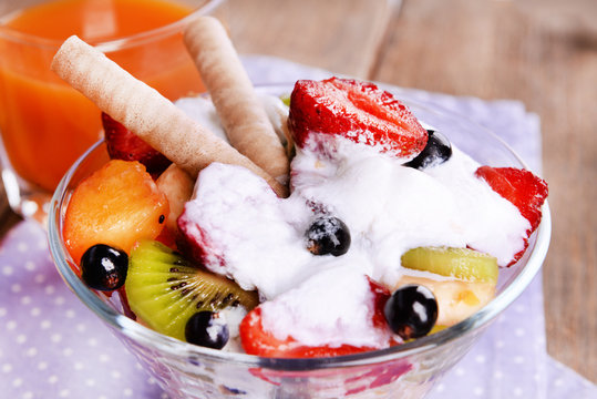Fresh fruits salad with ice cream in bowl and juice