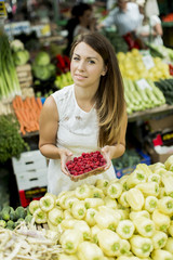 Young woman buying raspberries at the market