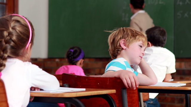 Little bored boy turning to the camera during class