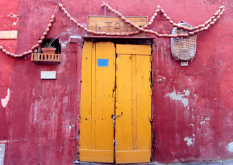 Una porta gialla su sfondo rosso a Procida - obrazy, fototapety, plakaty