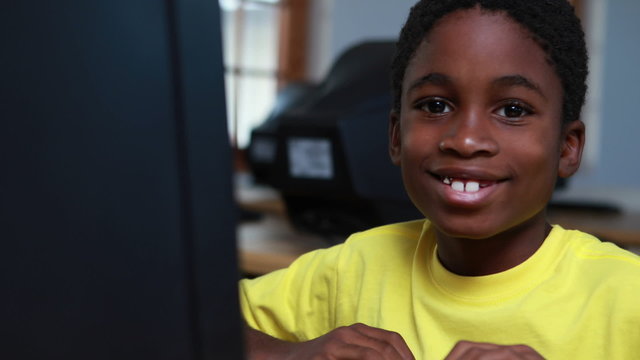 Little boy smiling at camera during computer class