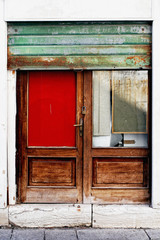 A wooden door in Venice with a red glass and a rusty green gate