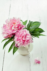 Pink peonies in retro vase on wooden table, vintage colors, tone