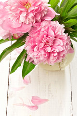 Pink peonies in retro vase on wooden table, closeup shot