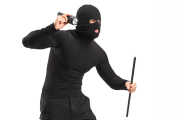 Robber with mask holding a flashlight and piece of pipe