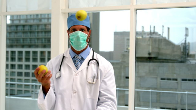 Doctor in mask juggling green apples