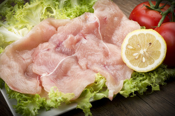 slices of chicken with salad on wood