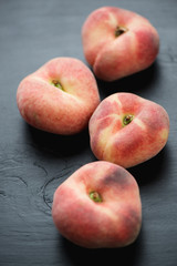 Close-up of saturn peaches, black wooden surface, vertical shot