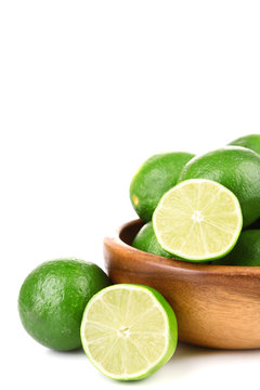 Fresh juicy limes in wooden bowl, isolated on white