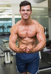 Fototapeta na wymiar Shirtless muscular man flexing muscles in gym