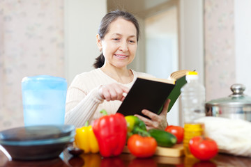 Obraz na płótnie Canvas woman with cookbook in the kitchen