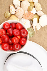 Plums, white hat and shells on wood and sand