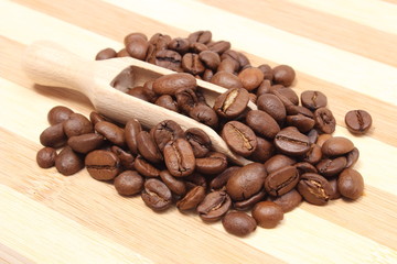 Heap of coffee on wooden spoon. Wooden background
