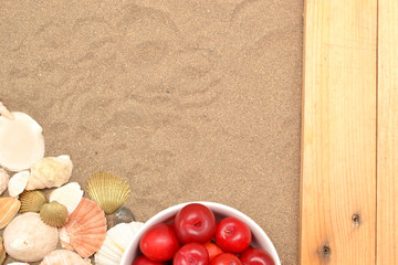 Plums and shells on wood and sand
