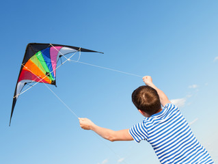 boy flies kite into blue sky