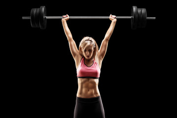 Muscular woman lifting a heavy barbell - obrazy, fototapety, plakaty