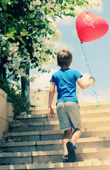 Obraz na płótnie Canvas cute 6 years old boy holding red balloon