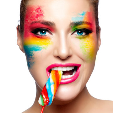 Beauty model face with fantasy makeup and colorful lollipop. Painted face. 