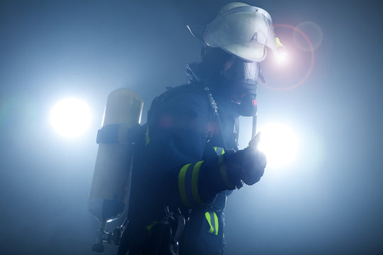 Feuerwehrfrau in Anzug und Atemschutzmaske mit Sauerstoffflasche Portr&auml;t