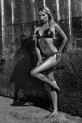 Sexy blonde bikini model posing at grungy wall.