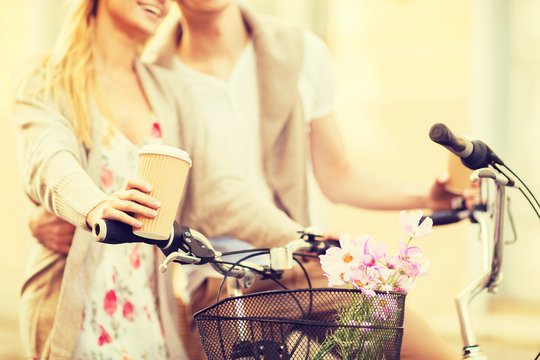 couple holding coffee and riding bicycle