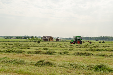 tractor turning raking cut hay in field