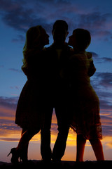 silhouette man between two women sunset