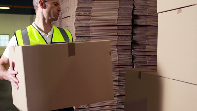 Warehouse worker stacking cardboard boxes