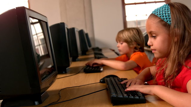 Cute pupils working on computers in classroom
