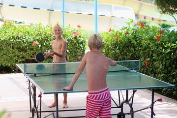 Two happy boys playing ping pong outdoors