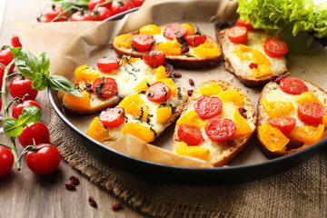 Tasty bruschetta with tomatoes on pan, on old wooden table