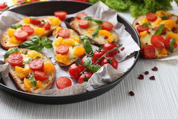 Tasty bruschetta with tomatoes in pan, on table